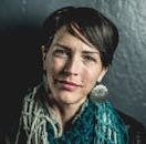 Close-up portrait of a stylish woman with short hair and bold earrings, exuding confidence.